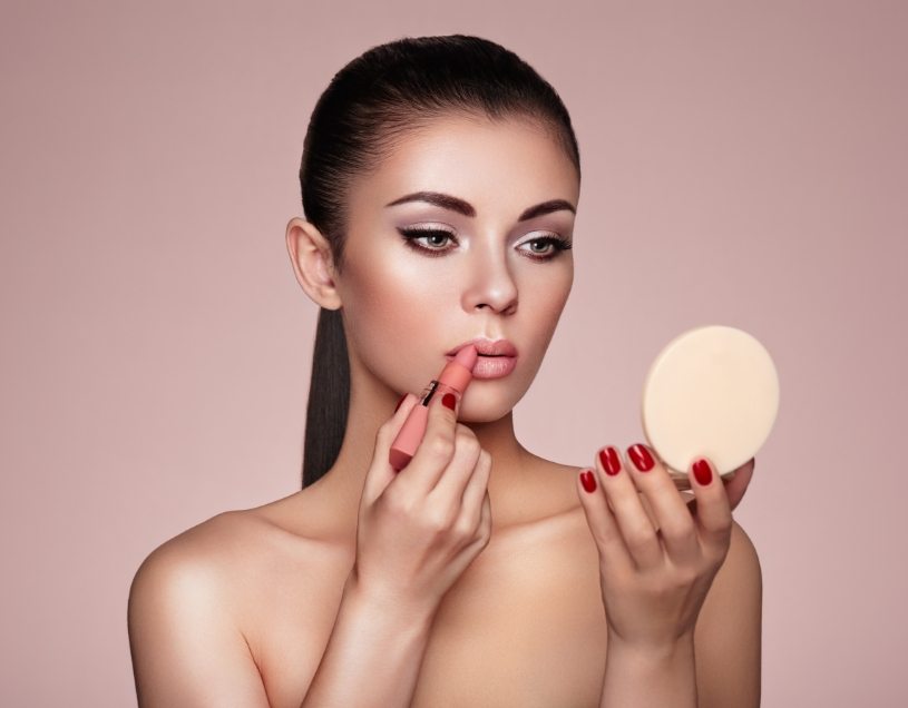 beautiful-woman-paints-lips-with-lipstick-PMB6YWP